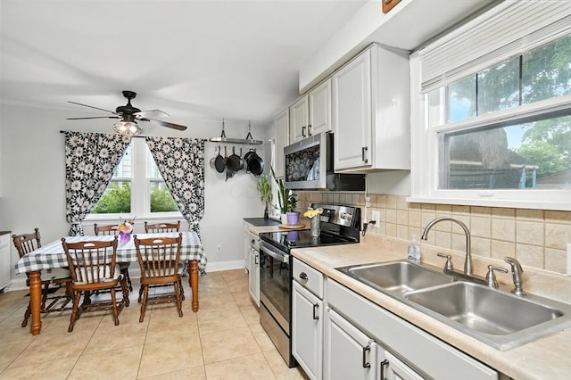 613 Salisbury Rd, Columbus, OH 43204 - kitchen featuring stainless steel appliances, a ceiling fan, backsplash, light tile patterned floors, and light countertops