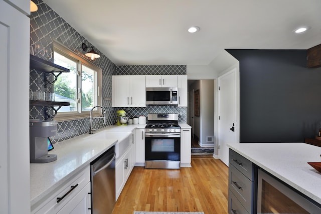 315 S Kellner Rd, Columbus, OH 43209 - kitchen featuring appliances with stainless steel finishes, beverage cooler, light wood-type flooring, decorative backsplash, and white cabinets