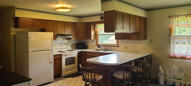 96 Summit St, Newark, OH 43055 - kitchen featuring white appliances, under cabinet range hood, a peninsula, light countertops, and tasteful backsplash