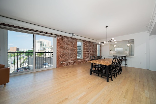 432 E Rich St Unit 3F, Columbus, OH 43215 - dining room featuring light wood finished floors, a chandelier, brick wall, and a view of city