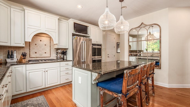 108 Hawks Cove Ct, Granville, OH 43023 - kitchen with appliances with stainless steel finishes, backsplash, white cabinets, a breakfast bar area, and light wood-style flooring