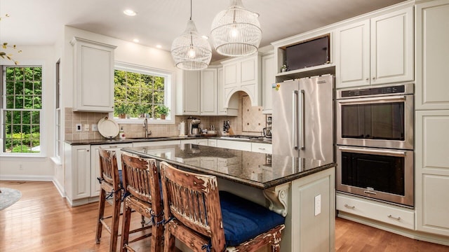 108 Hawks Cove Ct, Granville, OH 43023 - kitchen featuring stainless steel appliances, a chandelier, light wood-type flooring, a kitchen breakfast bar, and tasteful backsplash