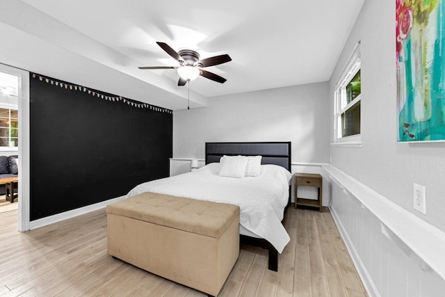 966 Larkstone Dr, Columbus, OH 43235 - bedroom with light wood-type flooring, multiple windows, wainscoting, a ceiling fan, and a decorative wall