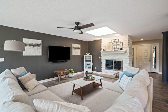 2500 Carriage Rd, Powell, OH 43065 - living room featuring wood finished floors, a skylight, a ceiling fan, a fireplace, and a textured ceiling