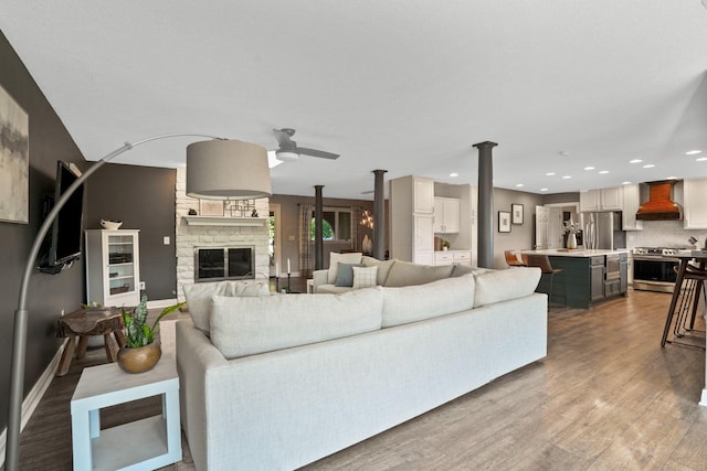 2500 Carriage Rd, Powell, OH 43065 - living room featuring a stone fireplace, a ceiling fan, wood finished floors, decorative columns, and recessed lighting
