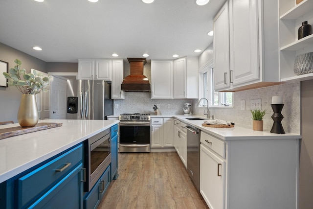 2500 Carriage Rd, Powell, OH 43065 - kitchen featuring blue cabinets, custom range hood, appliances with stainless steel finishes, white cabinets, and light countertops