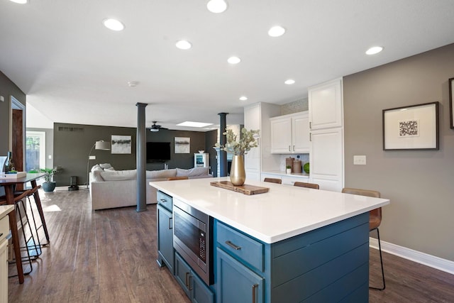 2500 Carriage Rd, Powell, OH 43065 - kitchen featuring white cabinetry, blue cabinetry, stainless steel microwave, a center island, and ceiling fan