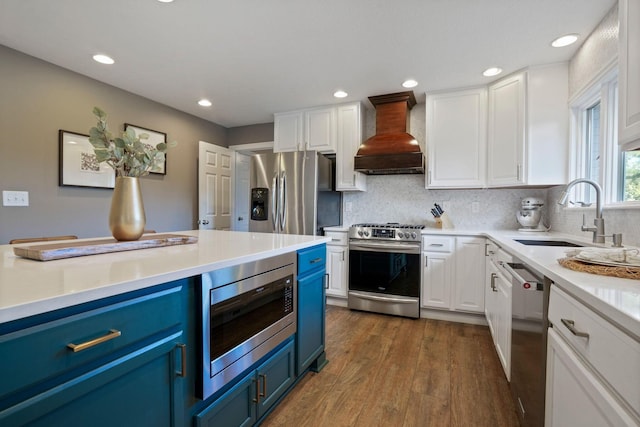 2500 Carriage Rd, Powell, OH 43065 - kitchen with blue cabinetry, appliances with stainless steel finishes, premium range hood, white cabinets, and recessed lighting