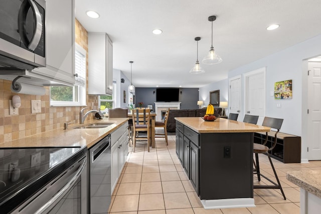 1271 Fareharm Dr, New Albany, OH 43054 - kitchen with appliances with stainless steel finishes, recessed lighting, a kitchen breakfast bar, tasteful backsplash, and hanging light fixtures