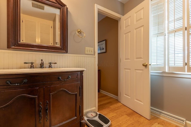409 N High St, Lancaster, OH 43130 - bathroom with a baseboard heating unit, a wainscoted wall, wood finished floors, and vanity