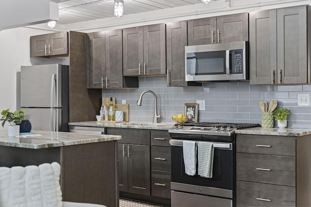 60 E Spring St Unit 220, Columbus, OH 43215 - kitchen with stainless steel appliances, backsplash, dark brown cabinets, and light stone counters