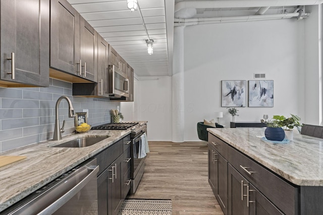 60 E Spring St Unit 220, Columbus, OH 43215 - kitchen with appliances with stainless steel finishes, dark brown cabinets, tasteful backsplash, and light wood-style floors
