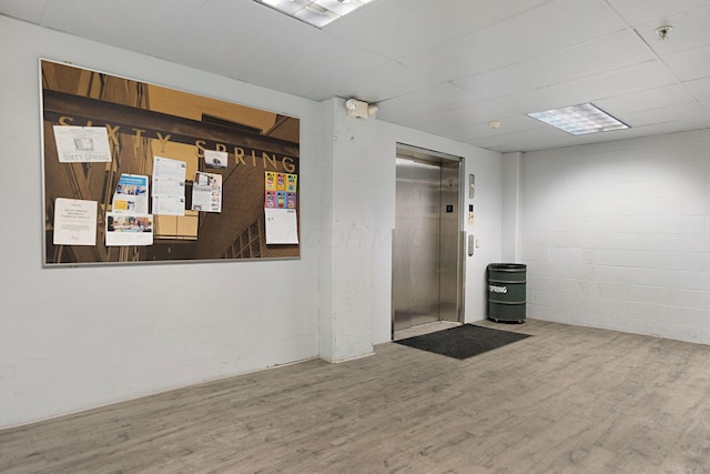 60 E Spring St Unit 220, Columbus, OH 43215 - unfurnished room featuring elevator, wood finished floors, fire sprinkler in ceiling, and concrete block wall