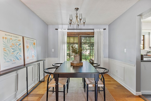 6666 Sharon Woods Blvd, Columbus, OH 43229 - dining area featuring a textured ceiling, light wood finished floors, a chandelier, and a wainscoted wall