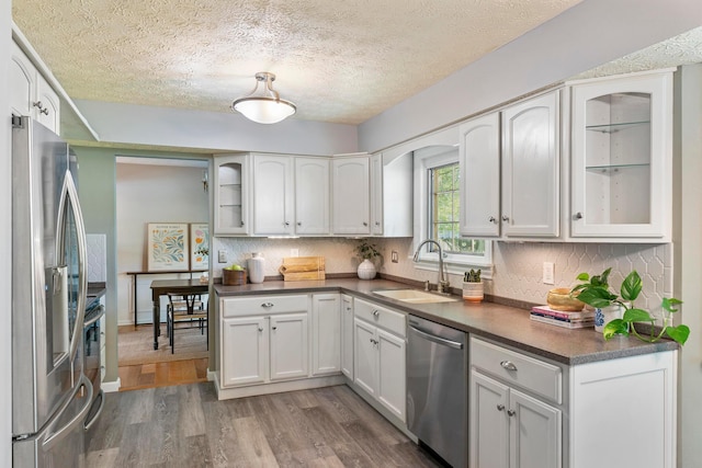 6666 Sharon Woods Blvd, Columbus, OH 43229 - kitchen with appliances with stainless steel finishes, wood finished floors, backsplash, glass insert cabinets, and a textured ceiling