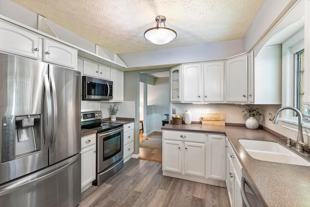 6666 Sharon Woods Blvd, Columbus, OH 43229 - kitchen featuring stainless steel appliances, wood finished floors, a textured ceiling, white cabinets, and decorative backsplash