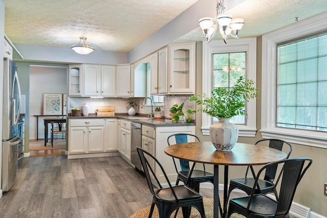 6666 Sharon Woods Blvd, Columbus, OH 43229 - kitchen featuring appliances with stainless steel finishes, wood finished floors, a chandelier, a textured ceiling, and dark countertops