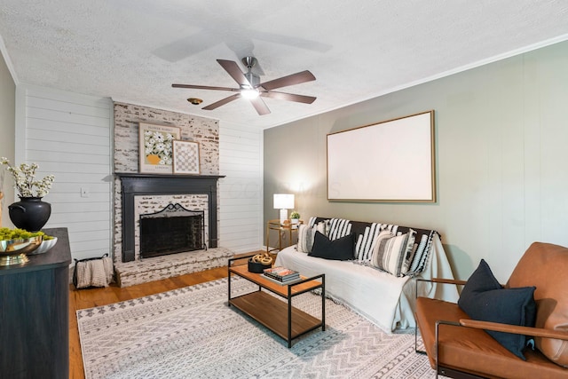 6666 Sharon Woods Blvd, Columbus, OH 43229 - living area featuring wood finished floors, a textured ceiling, a ceiling fan, a large fireplace, and ornamental molding