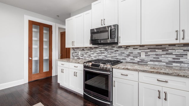 4721 W N Bank Rd, Buckeye Lake, OH 43008 - kitchen featuring appliances with stainless steel finishes, backsplash, dark wood-style flooring, light stone countertops, and white cabinetry