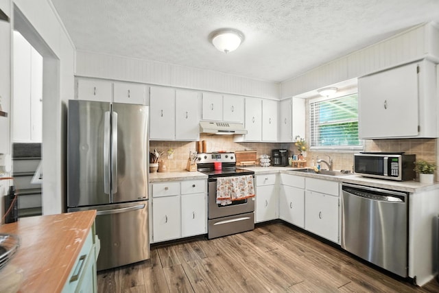 1978 Candlenut Cir, Grove City, OH 43123 - kitchen featuring appliances with stainless steel finishes, under cabinet range hood, white cabinets, tasteful backsplash, and a textured ceiling