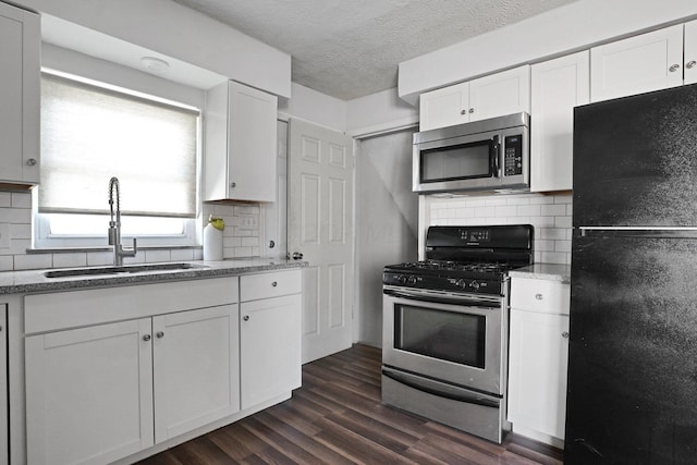 1458 E 22nd Ave, Columbus, OH 43211 - kitchen featuring stainless steel appliances, backsplash, white cabinets, dark wood finished floors, and a textured ceiling