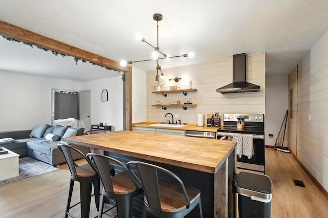 3139 Woonsocket St, Springfield, OH 45503 - kitchen featuring butcher block countertops, stainless steel electric range oven, light wood-type flooring, wall chimney range hood, and a kitchen breakfast bar