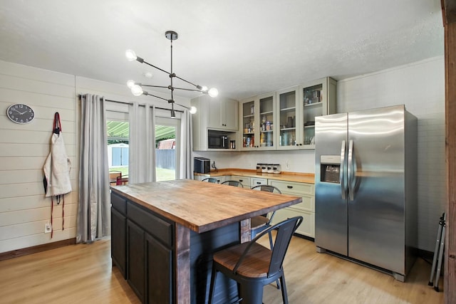 3139 Woonsocket St, Springfield, OH 45503 - kitchen with wood counters, stainless steel fridge with ice dispenser, light wood-type flooring, glass insert cabinets, and wooden walls