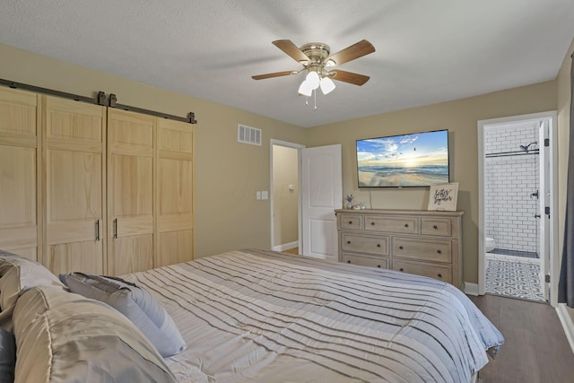 13722 Cobblestone Ln, Pickerington, OH 43147 - bedroom with dark wood-type flooring, connected bathroom, a barn door, ceiling fan, and a closet