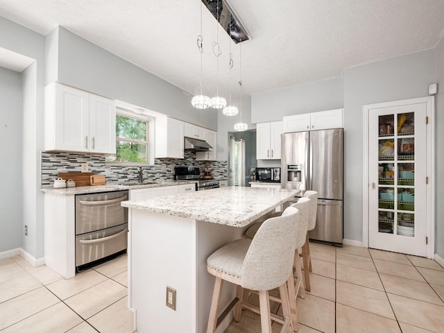 824 Lynnfield Dr, Westerville, OH 43081 - kitchen with stainless steel appliances, light tile patterned floors, a kitchen island, a breakfast bar area, and a textured ceiling