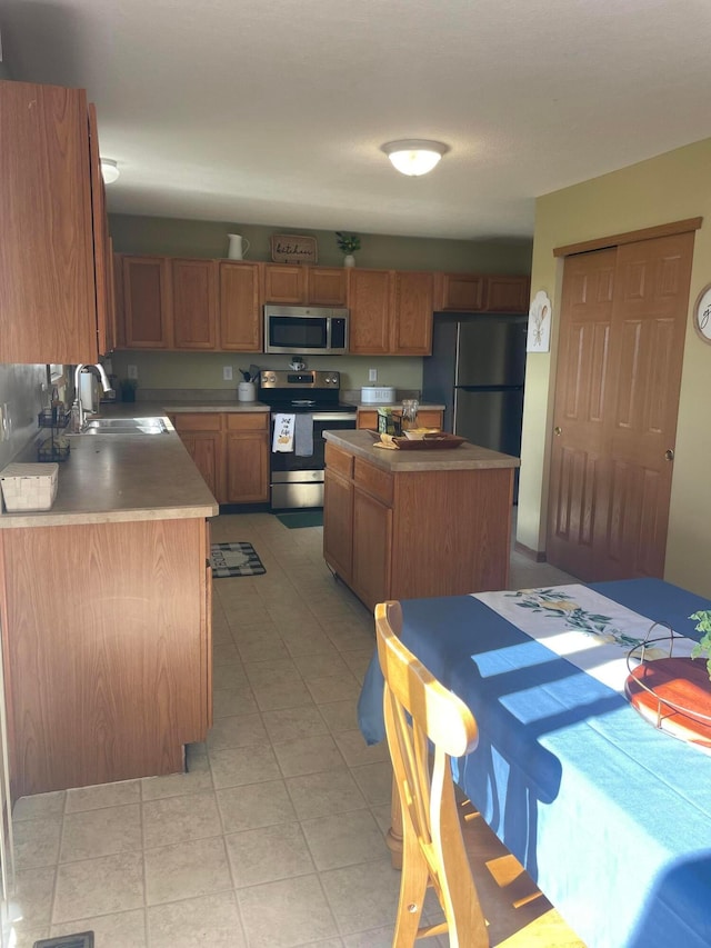 1889 Salt Lick Dr, Lancaster, OH 43130 - kitchen with appliances with stainless steel finishes, a center island, brown cabinets, and light tile patterned floors