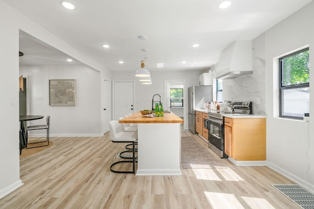 628 E Gates St, Columbus, OH 43206 - kitchen with appliances with stainless steel finishes, custom exhaust hood, wooden counters, a breakfast bar area, and recessed lighting