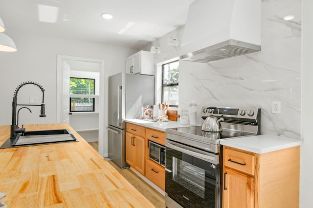 628 E Gates St, Columbus, OH 43206 - kitchen with wall chimney exhaust hood, appliances with stainless steel finishes, butcher block countertops, light wood-style flooring, and tasteful backsplash