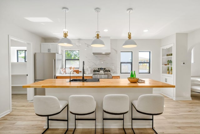 628 E Gates St, Columbus, OH 43206 - kitchen featuring butcher block countertops, appliances with stainless steel finishes, a kitchen island with sink, a kitchen breakfast bar, and recessed lighting