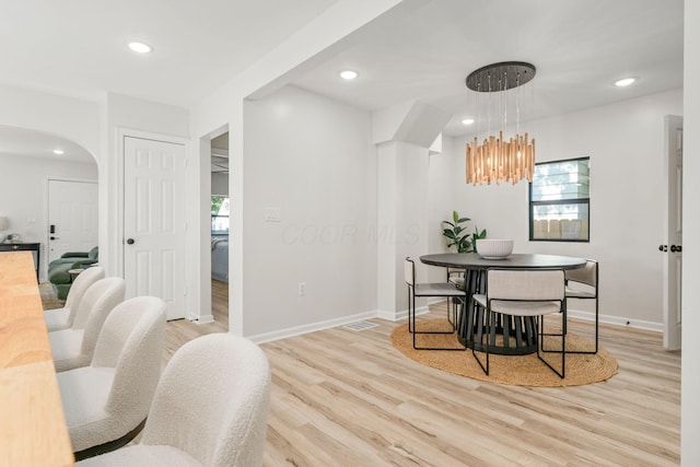 628 E Gates St, Columbus, OH 43206 - dining space featuring light wood finished floors, a chandelier, recessed lighting, and arched walkways
