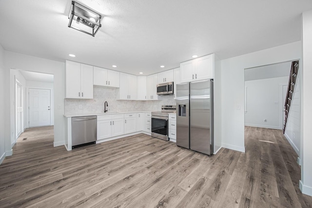 368 Woodview Dr, Chillicothe, OH 45601 - kitchen with appliances with stainless steel finishes, wood finished floors, white cabinets, backsplash, and recessed lighting