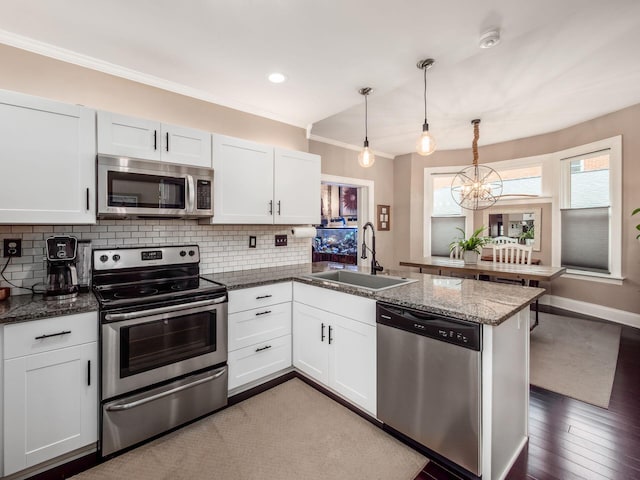 624 Oakwood Ave, Columbus, OH 43205 - kitchen featuring stainless steel appliances, a peninsula, decorative backsplash, ornamental molding, and white cabinets