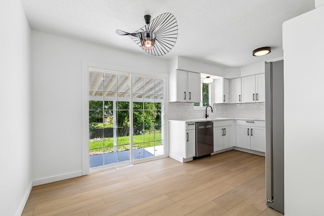 3048 Wallingford Ave, Columbus, OH 43231 - kitchen with stainless steel appliances, tasteful backsplash, light countertops, a textured ceiling, and light wood finished floors
