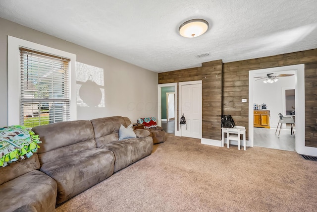 405 N Main St, Nevada, OH 44849 - living area featuring wooden walls, carpet, a textured ceiling, and a ceiling fan