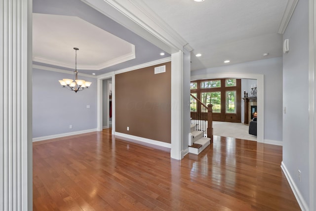 6820 Mahogany Dr, Galena, OH 43021 - empty room featuring wood finished floors, a chandelier, crown molding, stairway, and a glass covered fireplace