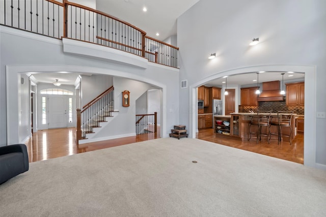 6820 Mahogany Dr, Galena, OH 43021 - living area with arched walkways, a towering ceiling, light wood-style floors, stairway, and light carpet