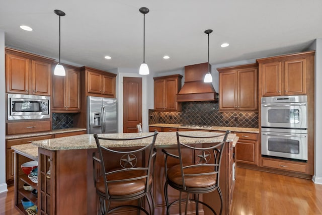 6820 Mahogany Dr, Galena, OH 43021 - kitchen featuring appliances with stainless steel finishes, custom exhaust hood, a center island, backsplash, and wood finished floors