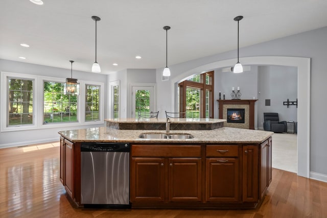 6820 Mahogany Dr, Galena, OH 43021 - kitchen with dishwasher, a center island with sink, wood finished floors, light stone countertops, and a glass covered fireplace
