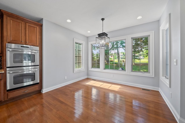6820 Mahogany Dr, Galena, OH 43021 - kitchen featuring stainless steel double oven, a chandelier, brown cabinetry, dark wood-type flooring, and decorative light fixtures