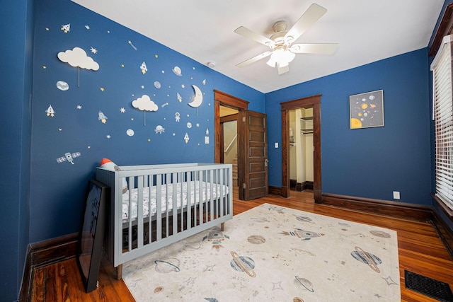199 E Gates St, Columbus, OH 43206 - bedroom with wood finished floors, a crib, and ceiling fan