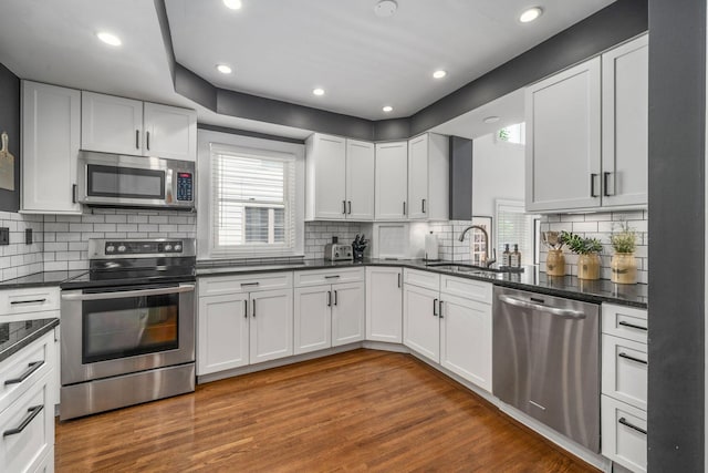 70 N Cassingham Rd, Columbus, OH 43209 - kitchen featuring appliances with stainless steel finishes, white cabinetry, wood finished floors, decorative backsplash, and recessed lighting