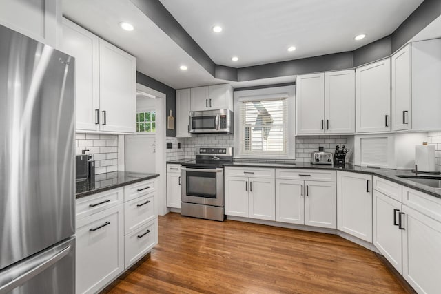 70 N Cassingham Rd, Columbus, OH 43209 - kitchen featuring appliances with stainless steel finishes, white cabinets, decorative backsplash, wood finished floors, and recessed lighting