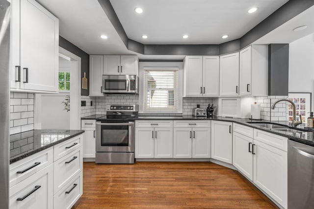 70 N Cassingham Rd, Columbus, OH 43209 - kitchen featuring appliances with stainless steel finishes, tasteful backsplash, white cabinets, wood finished floors, and dark stone countertops