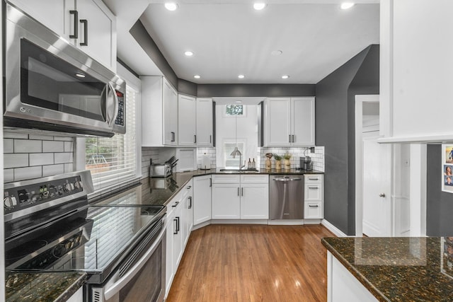 70 N Cassingham Rd, Columbus, OH 43209 - kitchen featuring stainless steel appliances, light wood-type flooring, dark stone counters, white cabinetry, and recessed lighting