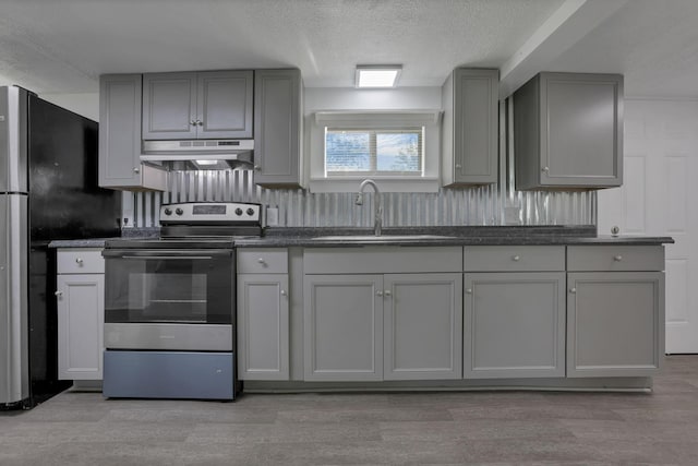 8898 Baker Rd, Stoutsville, OH 43154 - kitchen with under cabinet range hood, stainless steel electric stove, gray cabinets, dark countertops, and a textured ceiling