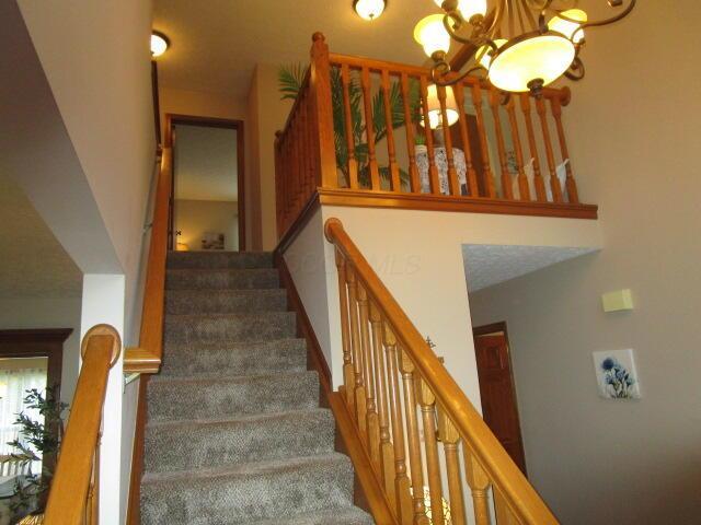 5669 Maplewood Ct, Lewis Center, OH 43035 - stairs featuring a chandelier